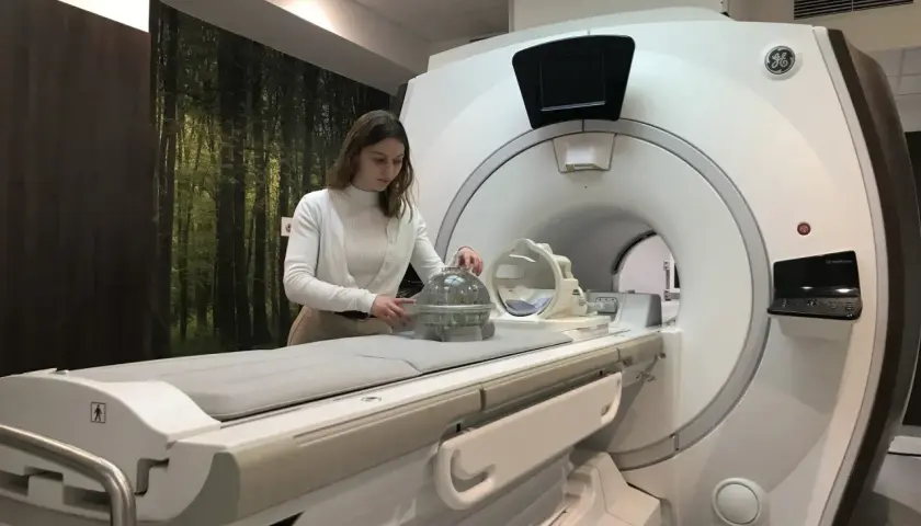 Kobieta przy aparacie MRI, przygotowująca fantom do badań. Praca w dziedzinie fizyki medycznej.