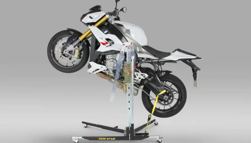 Biały motocykl BMW uniesiony na podnośniku motocyklowym centralnym.