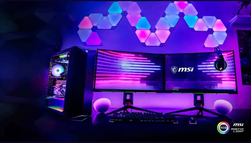 Gaming-Setup mit RGB-Beleuchtung, gesteuert durch MSI Mystic Light RGB Software. Ein PC, zwei Monitore und Wandpaneele leuchten in Pink und Blau.