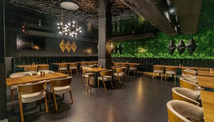 Elegancka restauracja z zieloną ścianą i nowoczesnym sufitem. Idealne miejsce na wykwintne białowieża jedzenie.