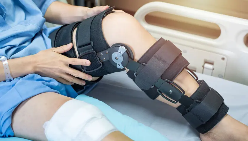 Patient mit Knieorthese, die von der Krankenkasse bezahlt wird, liegt im Krankenhausbett.