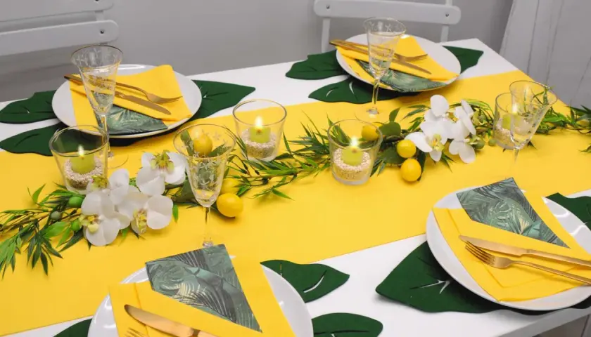 Eine sommerliche Tafel mit gelbem Läufer, Orchideen, Zitronen und Kerzen. Perfekt für schnelle Tischdeko Sommer.