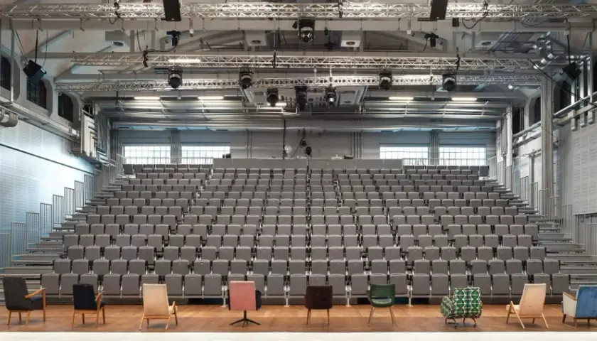 Widownia i scena Teatru Nowego w Warszawie. Puste, szare fotele czekają na widzów.