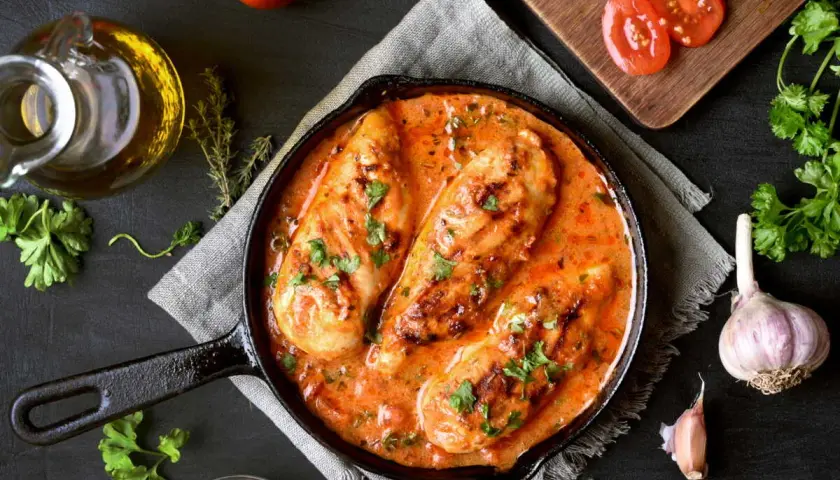 Poitrines de poulet en sauce crémeuse à la tomate, parsemées de persil. Un plat savoureux qui rappelle le poulet chorizo.