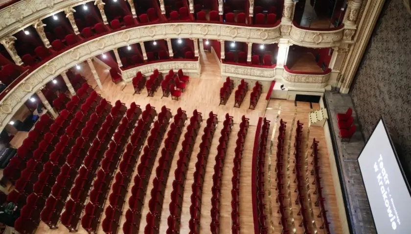 Widok z góry na bogato zdobione wnętrze Teatru im. Juliusza Słowackiego w Krakowie. Puste, czerwone fotele czekają na widzów, gotowe na kolejne spektakle.