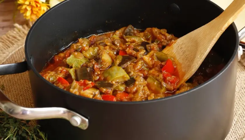 Une poêle remplie de ratatouille, comme dans le film, avec des légumes colorés et une cuillère en bois.