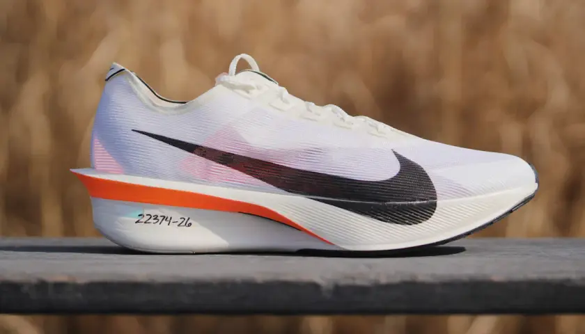 Białe buty treningowo startowe Nike z czarnym logo. Pomarańczowe akcenty i numeracja na podeszwie.