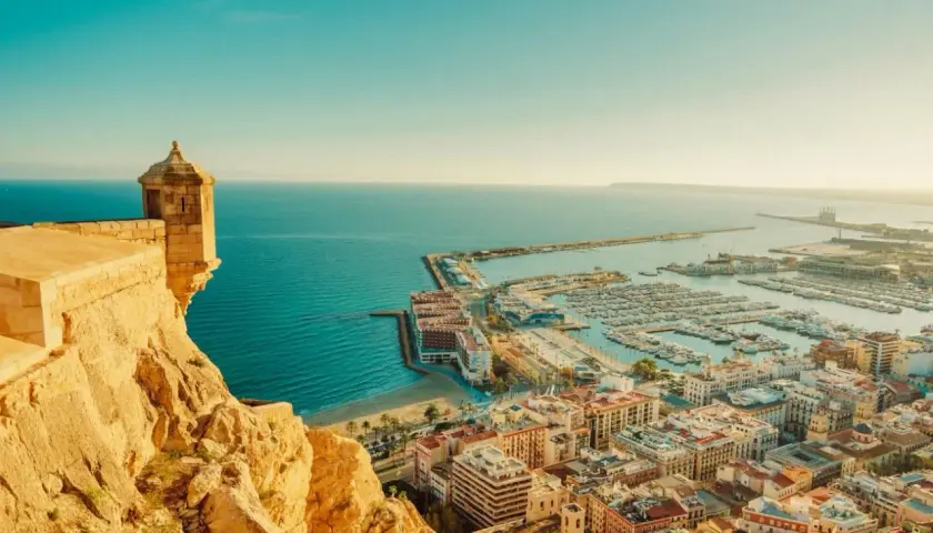 Vista panorámica de Alicante, con su castillo, el puerto deportivo lleno de barcos y el mar azul. Así es cual es la costa blanca.