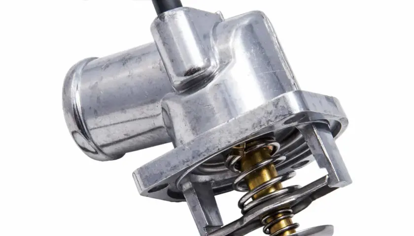 Metalowy termostat samochodowy z widocznym mechanizmem sprężynowym i czarną złączką.