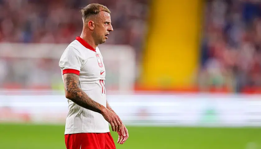 Piłkarz Kamil Grosicki w białej koszulce i czerwonych spodenkach, z tatuażami na ramieniu. Jego majątek budowany latami na boisku.