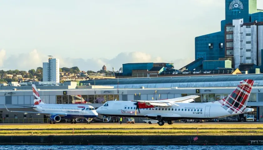 British Airways und Loganair Flugzeuge am London Flughafen. Im Hintergrund die markante Lyle's Golden Syrup Fabrik.