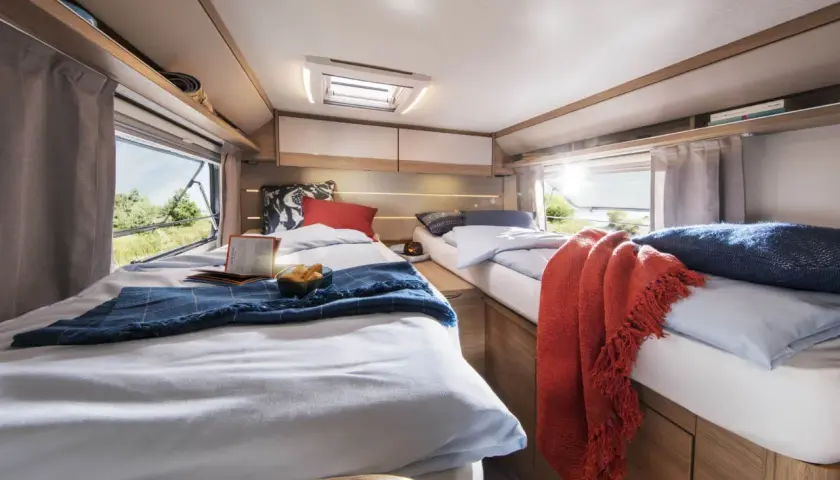 Deux lits jumeaux confortables, aménagés comme un lit à la française, invitent au repos dans ce camping-car lumineux.