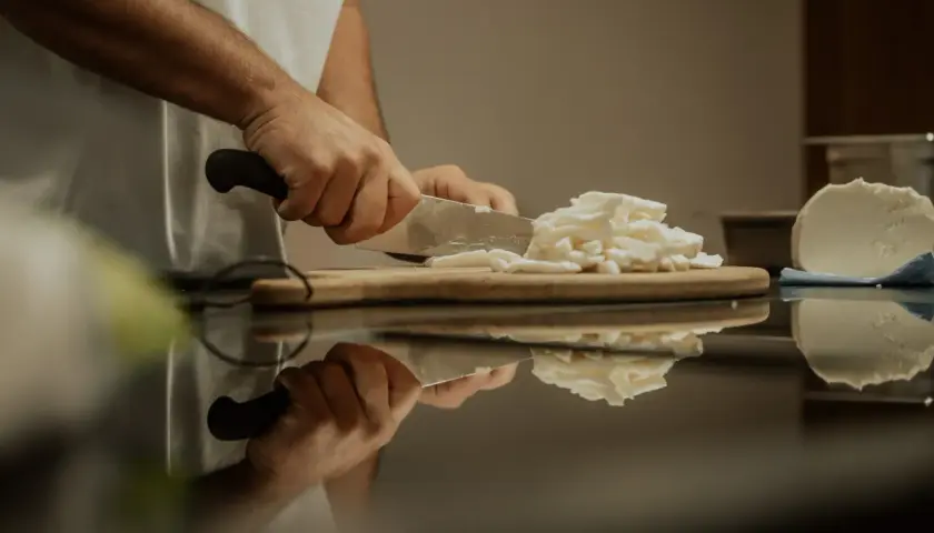 Hände schneiden Fior di Latte Mozzarella für eine Pizza.