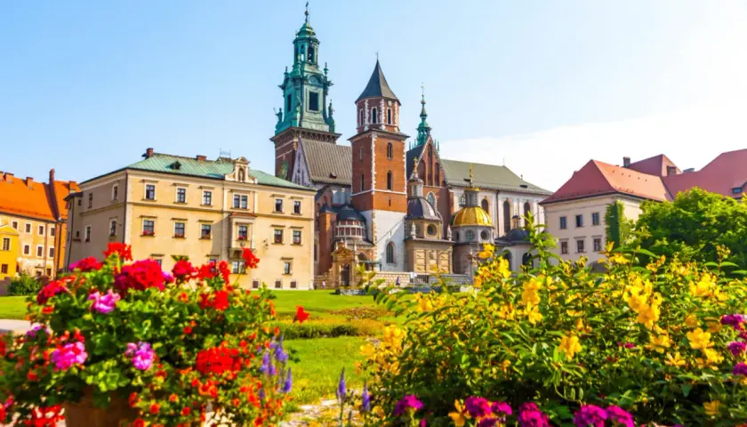 Krakowski Wawel, wpisany na **UNESCO listę polską**, w otoczeniu kwitnących kwiatów.