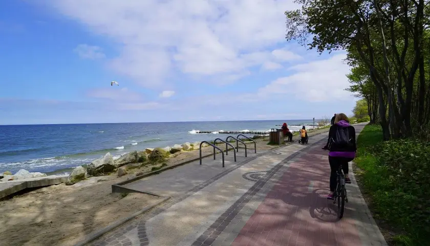 Rowerzystka na ścieżce nad morzem. Zastanawiasz się, ile kilometrów jest z Koszalina do Kołobrzegu? Ta malownicza trasa zachęca do aktywnego wypoczynku.
