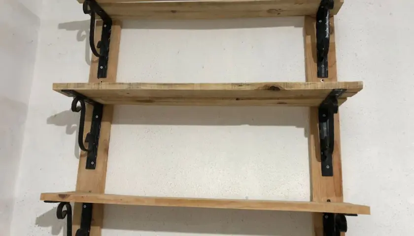 Scaffali in legno fai da te, con staffe nere decorative, perfetti per un tocco rustico.