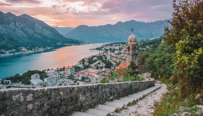 Escaleras de piedra con vistas a la bahía de Kotor al atardecer. Un lugar ideal donde viajar en julio barato.