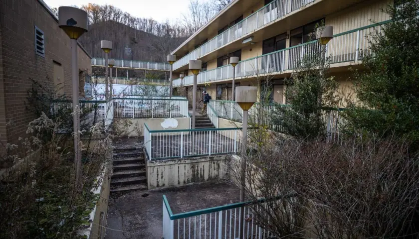 Opuszczone miasta w Polsce: zaniedbany hotel z widokiem na wzgórza, zarośnięte schody i zniszczone balustrady.