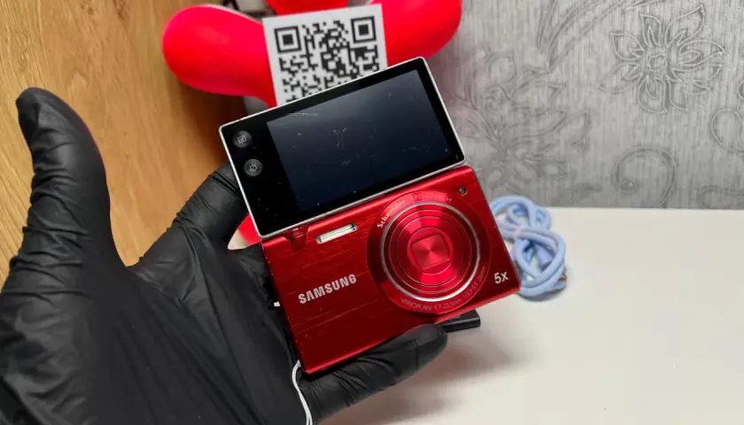 Czerwony aparat Samsung MV800 z obracanym ekranem, trzymany w czarnej rękawiczce.