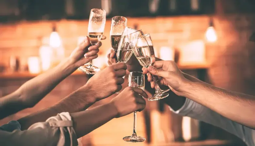 Des mains lèvent des flûtes de champagne pour trinquer. Une belle façon de célébrer, comme pour apprendre comment trinquer en allemand avec un "Prost !".