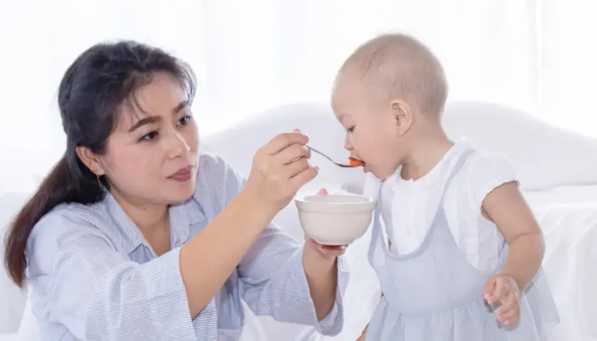 Madre alimenta a su bebé con cuchara. Mi bebé come bien pero no engorda, aunque se ve feliz y saludable.