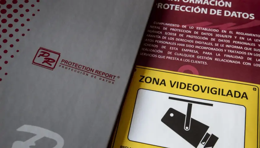 Documentos sobre protección de datos y un cartel de "Zona Videovigilada", parte de una feria de seguridad.