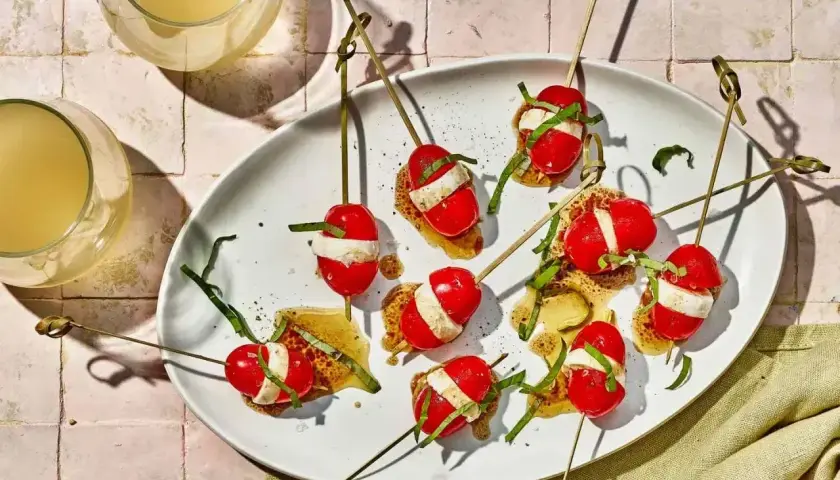 Proste przepisy na przekąski w 15 minut: szaszłyki caprese z pomidorków, mozzarelli i bazylii na chrupiącym grzanie.