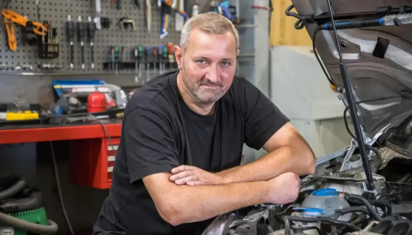 Mechanik przy otwartej masce Passata B6, który nie odpala i nie kręci.