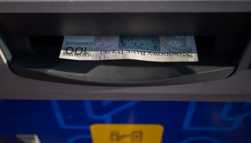 Sto złotych w banknocie wychodzi z bankomatu. To mój etatowy dochód, który właśnie wypłaciłem.