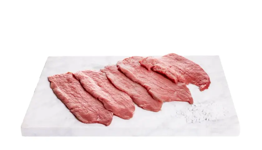 Fettine di vitello pronte per gustose ricette. Carne fresca su tagliere di marmo con sale grosso.