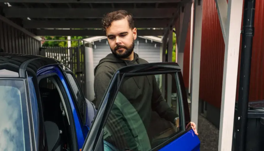 Man med skägg öppnar dörren till en blå bil. Kanske dags att tänka på att måste man serva bilen varje år för att den ska hålla sig i toppskick.