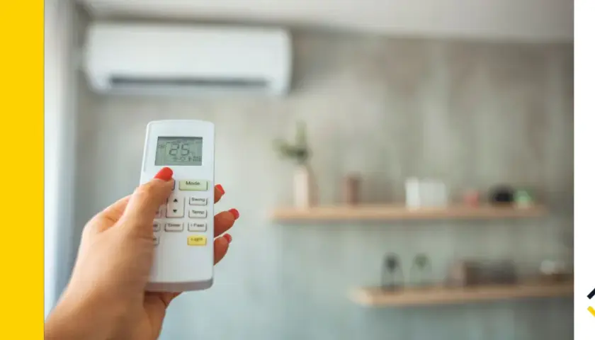 Mano con mando a distancia de aire acondicionado, ajustando la temperatura. Ideal para calcular potencia aire acondicionado y optimizar el confort.