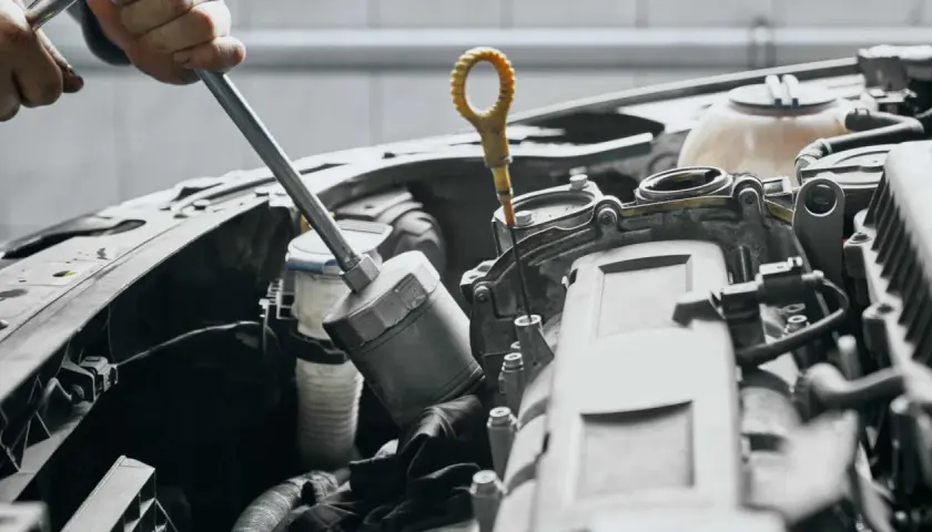 Mechanik sprawdza poziom oleju, co może być jednym z objawów uszkodzonej pompy oleju.