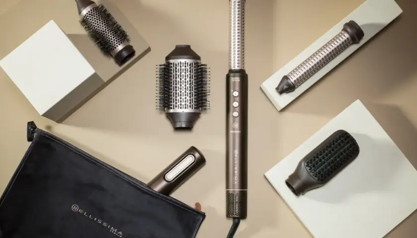 Herramientas para un blow out hair perfecto: cepillos redondos, un rizador y un cepillo plano, junto a un estuche.