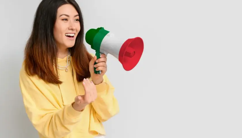 Ragazza con megafono tricolore italiano, che annuncia "mercoledì in inglese pronuncia" con entusiasmo.