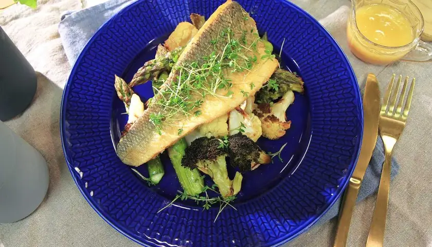 En läcker havsabborre med rostade grönsaker, perfekt för ett enkelt havsabborre recept. Serveras med en ljus sås och gyllene bestick.