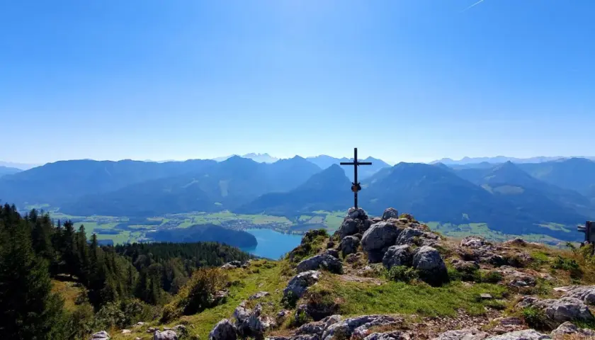 Gipfelkreuz mit Blick auf einen See und Berge. Perfekt für Salzkammergut wandern.