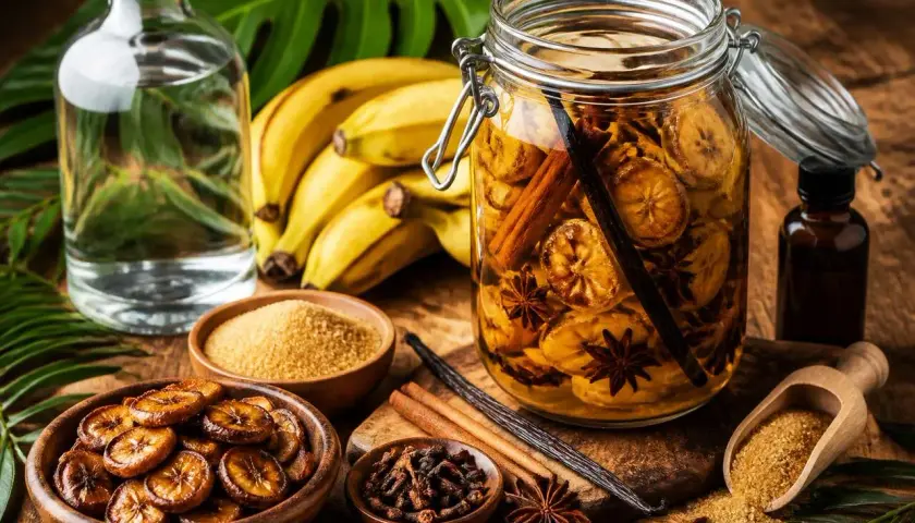 Préparation d'une recette rhum arrangé banane : bananes, sucre, cannelle, anis étoilé, vanille et rhum blanc.
