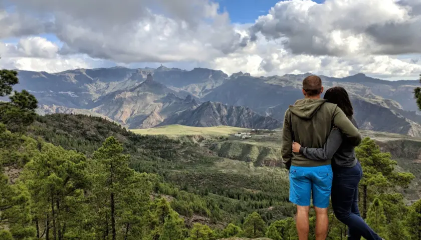 Para zakochanych podziwia malowniczy krajobraz podczas trekkingu na Gran Canarii. Góry, lasy i chmury tworzą spektakularny widok.