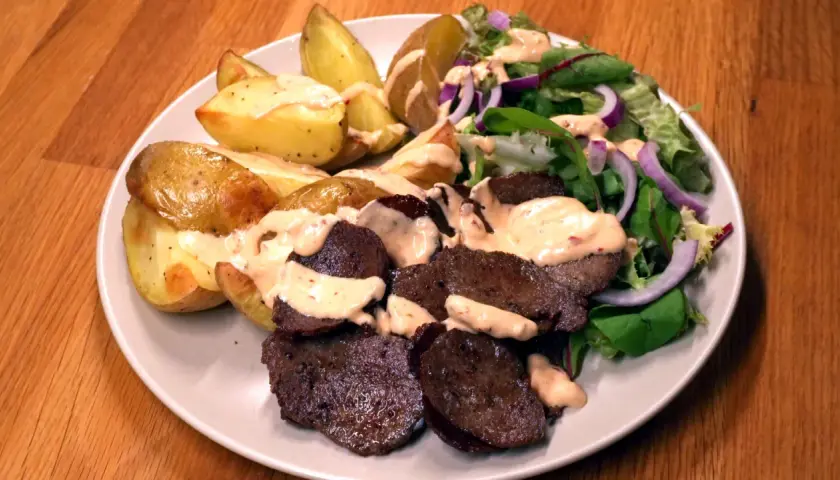 En tallrik med ugnsrostad potatis, saftig kebab och en fräsch sallad med rödlök. En perfekt kebab på plåt för en härlig middag.