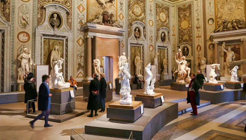 Salle ornée de sculptures classiques à la Villa Borghese. Des visiteurs admirent des œuvres d'art dans un décor somptueux.