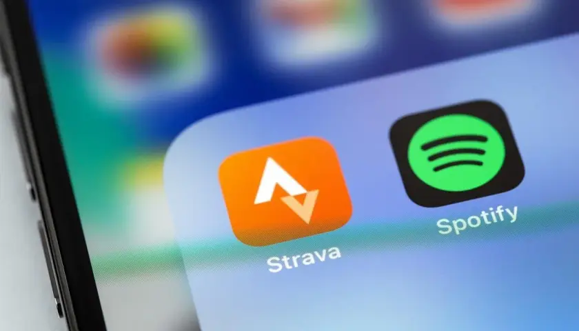 Ikona aplikacji Strava, idealna do śledzenia tras rowerowych, obok Spotify na ekranie smartfona.