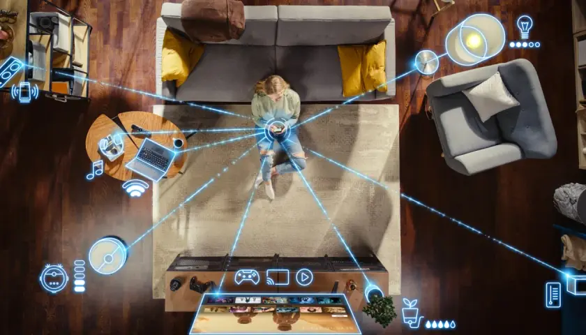 Mujer controlando electrodomésticos domóticos con su móvil. Luces, aspiradora, TV y más conectados.