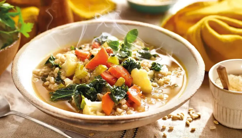 Un humeante tazón de sopa de cebada con kale, zanahorias y patatas. ¡Perfecto para tus recetas con kale!