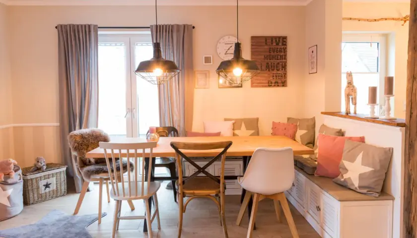 Gemütliches Esszimmer gestalten: Holztisch, Bank mit Kissen, verschiedene Stühle und Wanddeko schaffen einladendes Ambiente.