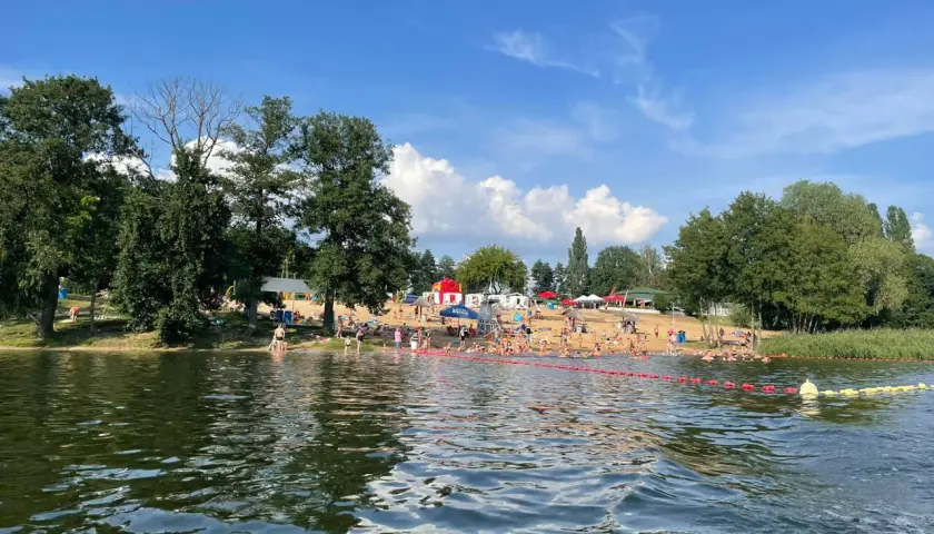 Słoneczny dzień nad jeziorem, pełnym ludzi kąpiących się i opalających. To jedne z fajnych miejsc nad wodą mazowieckie.