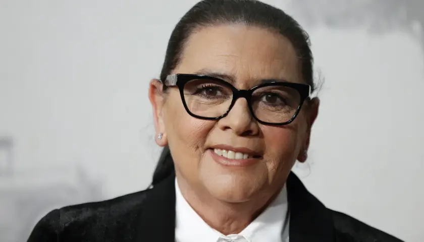 María del Monte, con gafas negras y una sonrisa amable, luce un traje elegante.