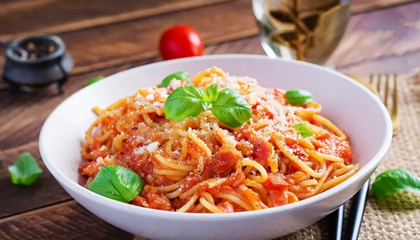 Un piatto di spaghetti alla corte d'assise, conditi con pomodoro fresco e basilico, spolverati di parmigiano.