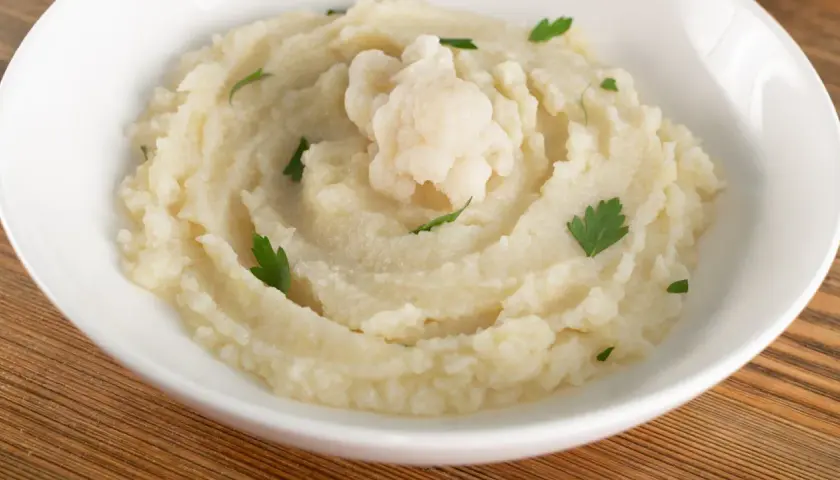 Aksamitne puree z kalafiora, udekorowane gałązką świeżej natki. Idealne jako lekki dodatek do obiadu.