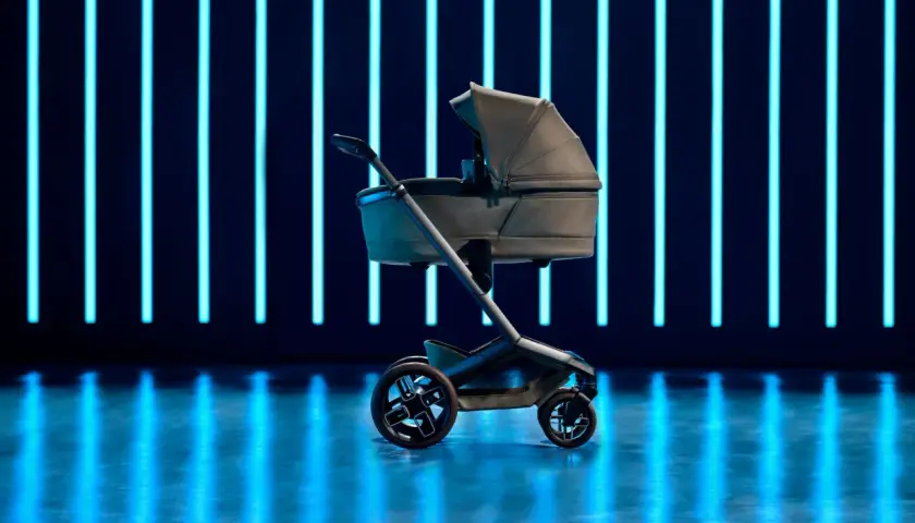 Elegancki wózek dziecięcy Maxi Cosi Fame na tle neonowych, niebieskich świateł.